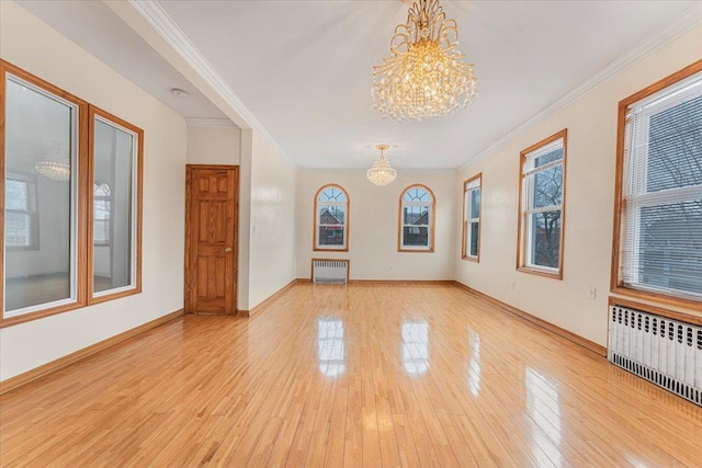 spare room featuring light wood-style floors, crown molding, radiator heating unit, and an inviting chandelier