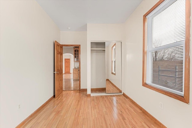 unfurnished bedroom with baseboards, a closet, and light wood-style floors