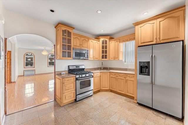 kitchen featuring arched walkways, recessed lighting, stainless steel appliances, baseboards, and glass insert cabinets