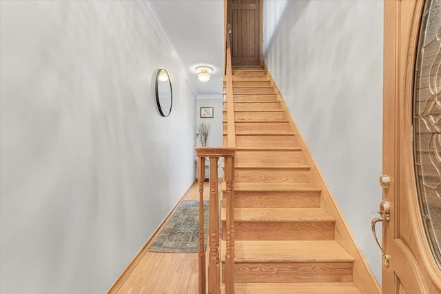 stairs featuring ornamental molding, baseboards, and wood finished floors