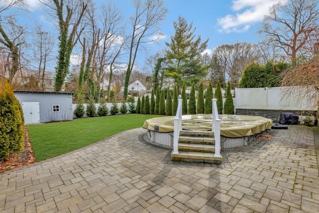 view of patio with a covered hot tub, fence, and an outdoor structure