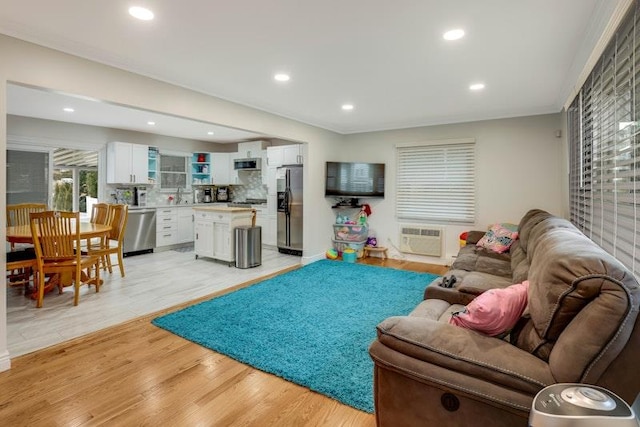 living room with a wall unit AC, light wood-type flooring, and recessed lighting