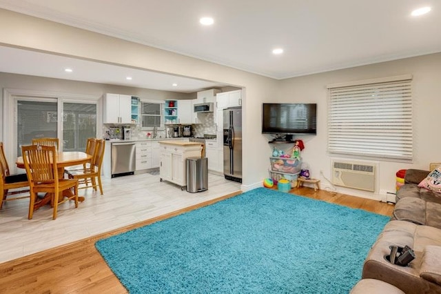 living area with light wood-type flooring, a wall mounted air conditioner, recessed lighting, and a baseboard radiator