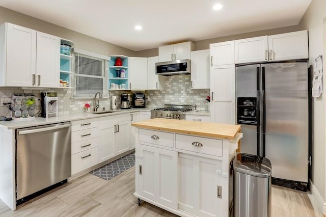 kitchen featuring white cabinets, wooden counters, appliances with stainless steel finishes, open shelves, and tasteful backsplash