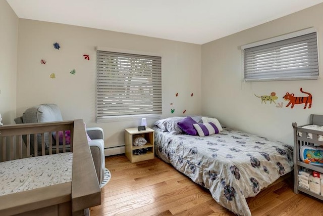 bedroom featuring baseboard heating and hardwood / wood-style flooring