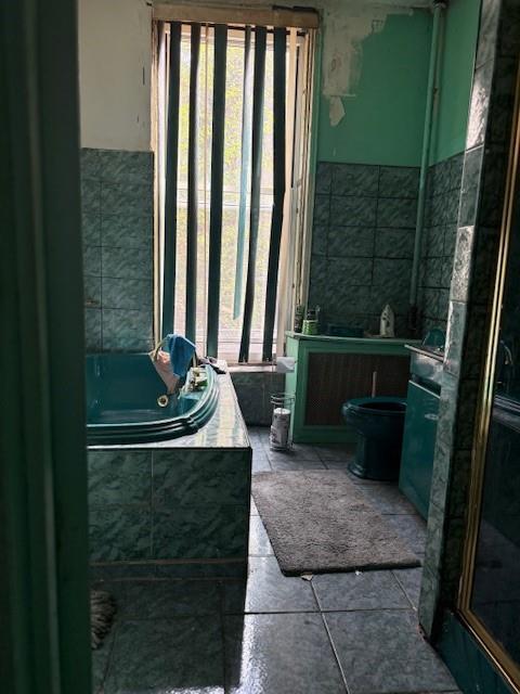 412 W 146th St, New York Manhattan, NY 10031 - bathroom featuring toilet, a jetted tub, a wealth of natural light, and tile patterned flooring