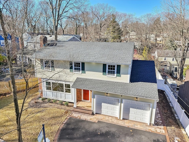 traditional-style house with a shingled roof, fence, and aphalt driveway