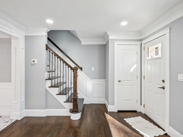 foyer featuring ornamental molding, stairway, wood finished floors, and a decorative wall