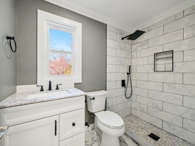 bathroom featuring toilet, vanity, marble finish floor, tiled shower, and crown molding