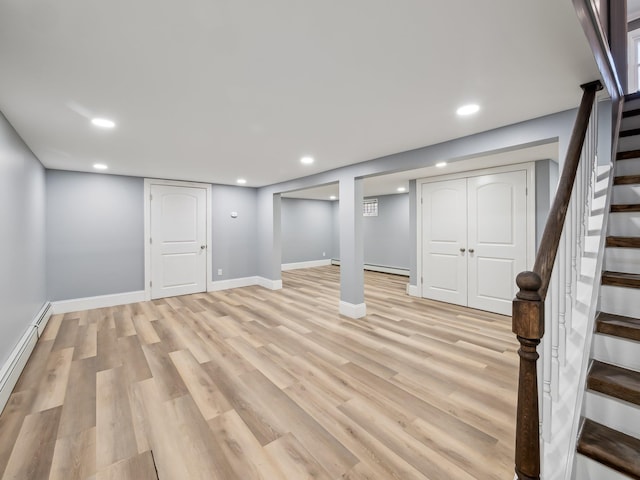 finished below grade area with recessed lighting, a baseboard heating unit, baseboards, stairway, and light wood-type flooring