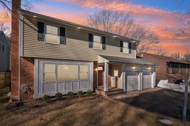 view of front facade featuring a garage, a chimney, aphalt driveway, and brick siding