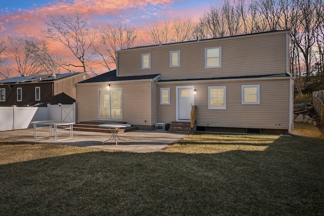 back of property with entry steps, a patio area, fence, and a lawn