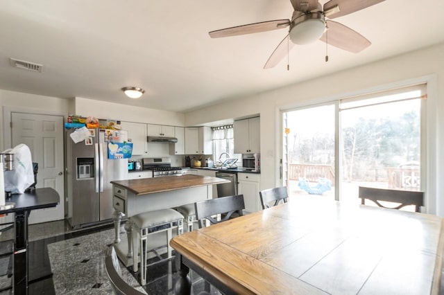 kitchen with visible vents, butcher block counters, a kitchen island, appliances with stainless steel finishes, and under cabinet range hood