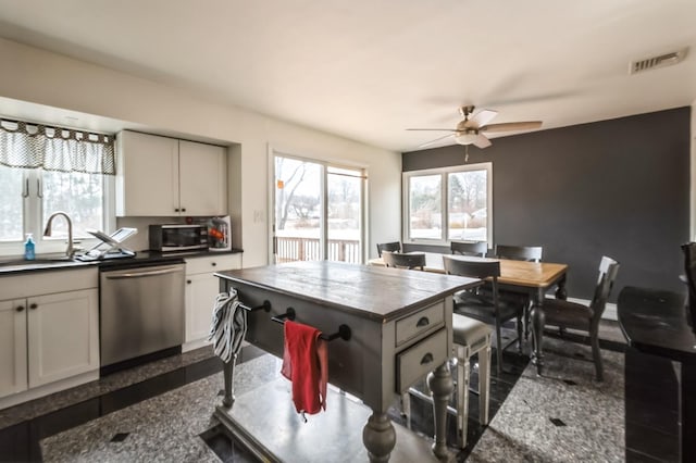 kitchen featuring stainless steel appliances, granite finish floor, dark countertops, and a sink