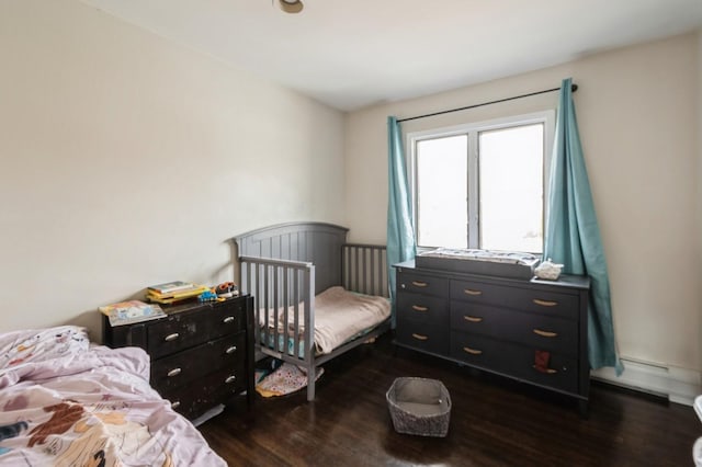 bedroom featuring a baseboard heating unit and dark wood finished floors