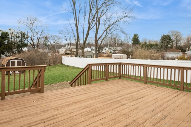 wooden terrace with a yard, a fenced backyard, a storage unit, and an outbuilding