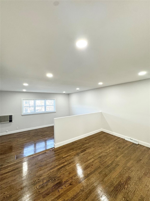 below grade area featuring dark wood-type flooring, recessed lighting, visible vents, and baseboards