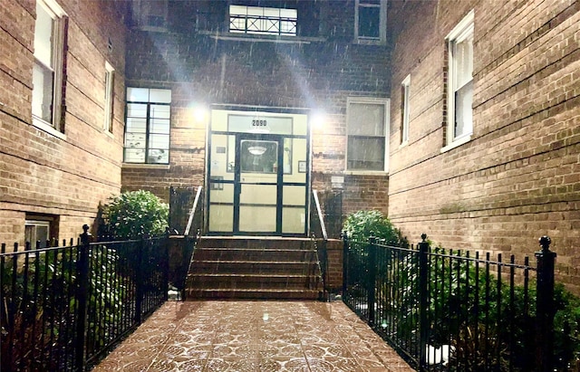 doorway to property with brick siding and fence