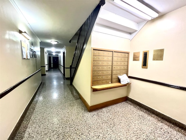 hallway featuring mail area, baseboards, and speckled floor