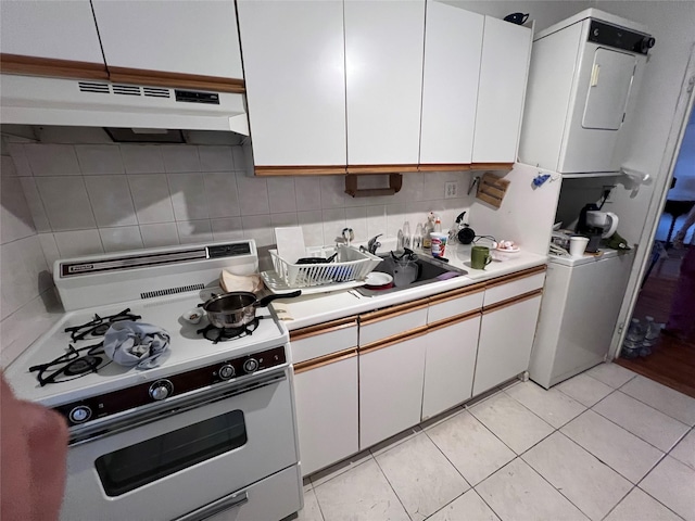 2090 Barnes Ave Unit 2H, Bronx, NY 10462 - kitchen featuring white range with gas stovetop, stacked washing machine and dryer, under cabinet range hood, light countertops, and white cabinets