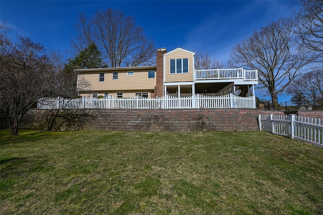 rear view of property featuring a deck, a fenced backyard, a lawn, and a chimney