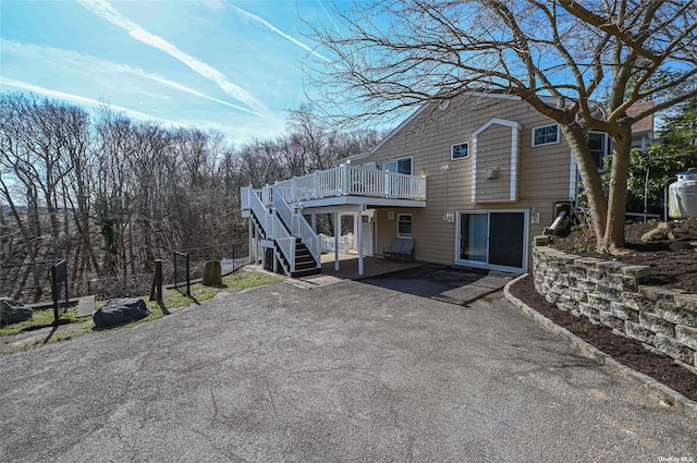 view of front facade featuring fence, a patio, a wooden deck, and stairs