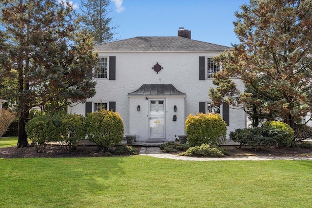 colonial inspired home featuring a chimney and a front yard