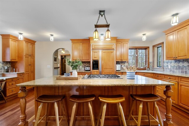 5 Shingle House Rd, Millwood, NY 10546 - kitchen with decorative backsplash, a kitchen island, arched walkways, paneled built in refrigerator, and stainless steel gas stovetop