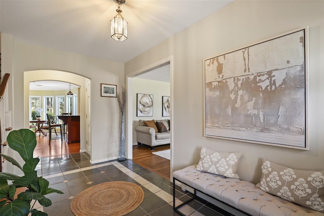 living room featuring dark tile patterned floors, baseboards, and arched walkways