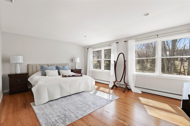 bedroom with lofted ceiling, wood finished floors, and a baseboard radiator