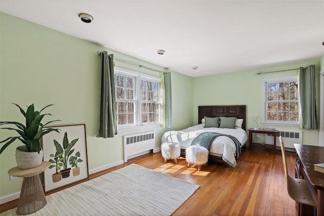 bedroom with baseboards, radiator, and wood finished floors