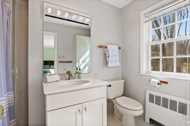 bathroom with vanity, toilet, a healthy amount of sunlight, and radiator heating unit