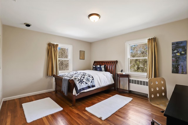 bedroom featuring baseboards, radiator, and wood finished floors