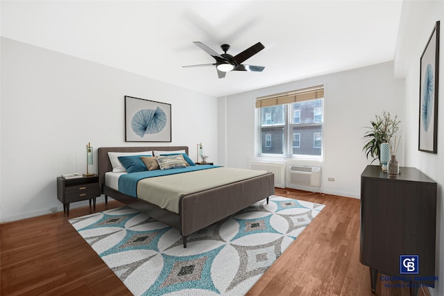 bedroom featuring baseboards, radiator heating unit, ceiling fan, an AC wall unit, and light wood-style floors