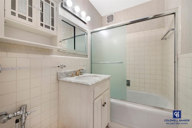 full bath featuring enclosed tub / shower combo, vanity, visible vents, and tile walls