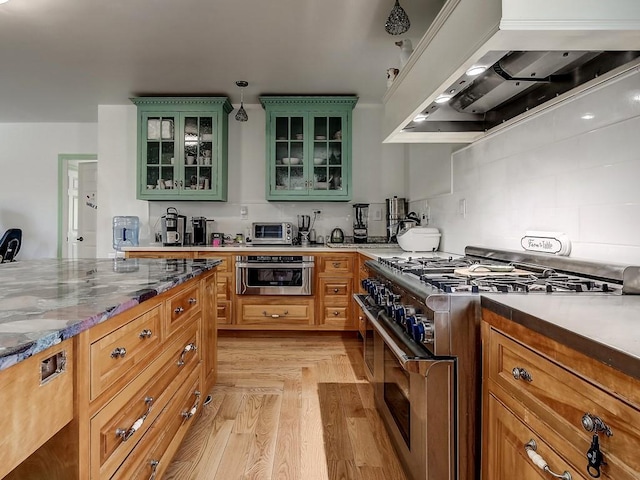 kitchen featuring stainless steel appliances, light wood-style flooring, green cabinets, glass insert cabinets, and premium range hood