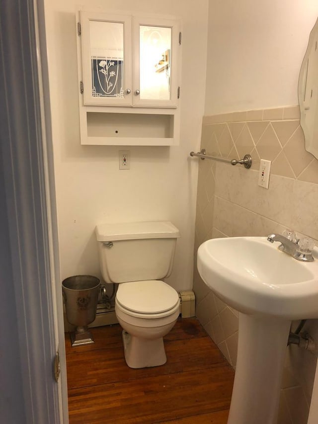 bathroom with toilet, wood finished floors, and tile walls