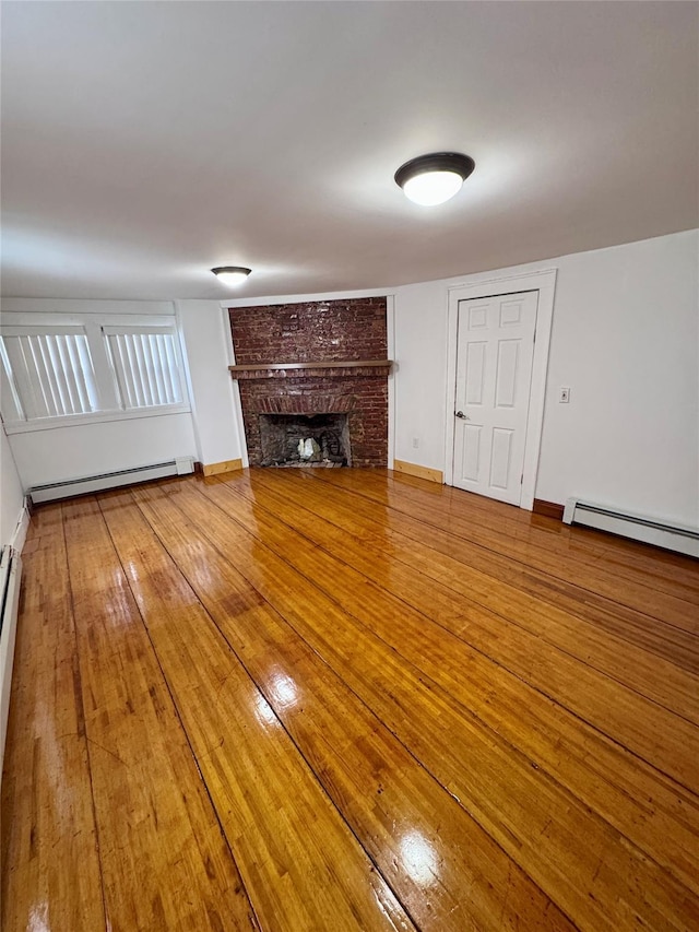 unfurnished living room with baseboard heating, baseboards, a fireplace, and hardwood / wood-style floors