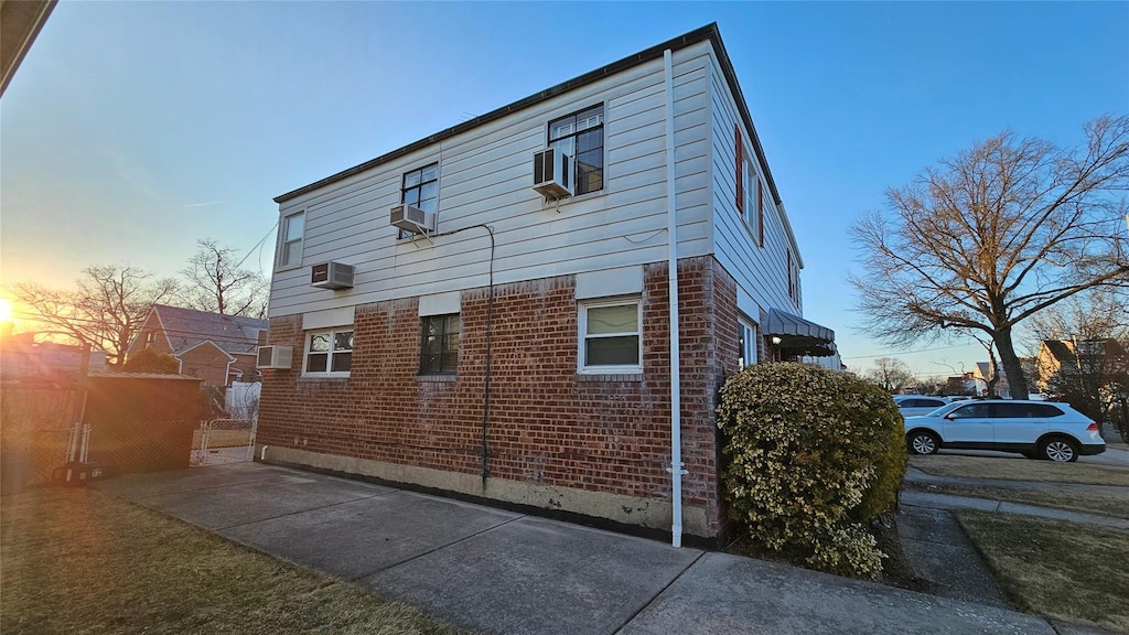 view of side of property with a wall mounted AC and brick siding