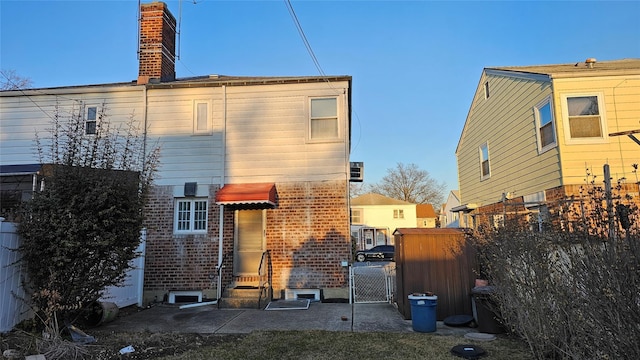 back of property featuring a gate, fence, and brick siding