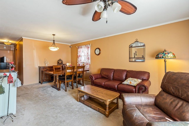 living area featuring a ceiling fan, ornamental molding, and carpet flooring