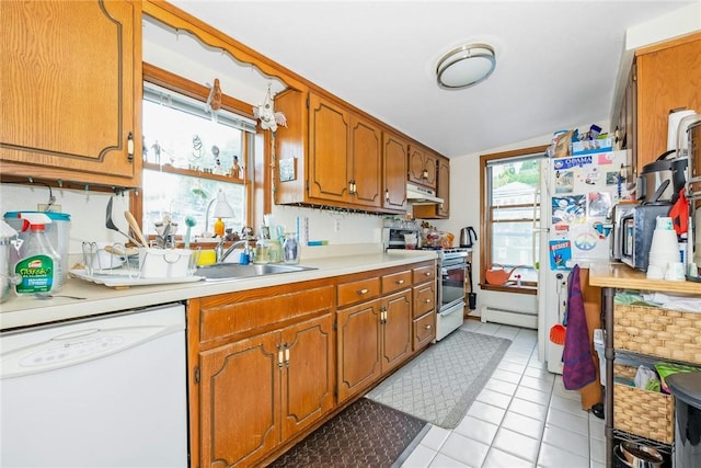 kitchen featuring a baseboard heating unit, stainless steel appliances, a sink, light countertops, and brown cabinetry