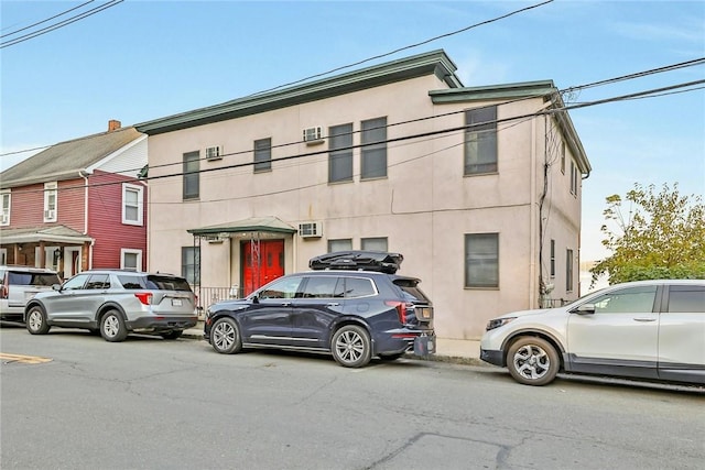 view of front of house featuring a wall mounted AC and stucco siding