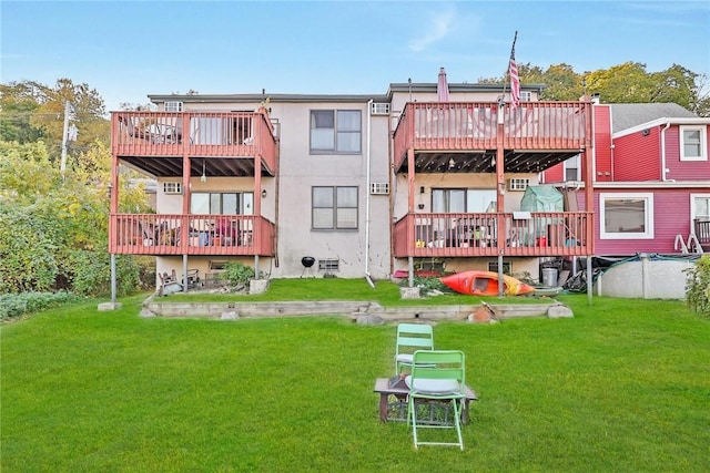 back of property featuring a deck, a lawn, and stucco siding