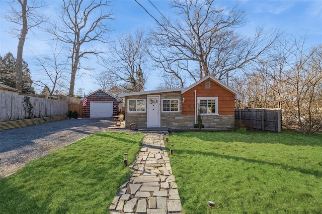 view of front facade with gravel driveway, an outdoor structure, a front lawn, and fence