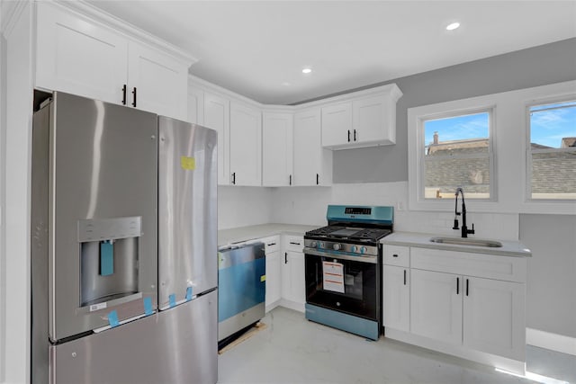 kitchen featuring light countertops, decorative backsplash, appliances with stainless steel finishes, white cabinets, and a sink