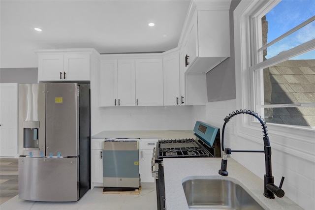 kitchen with stainless steel appliances, recessed lighting, light countertops, white cabinetry, and a sink