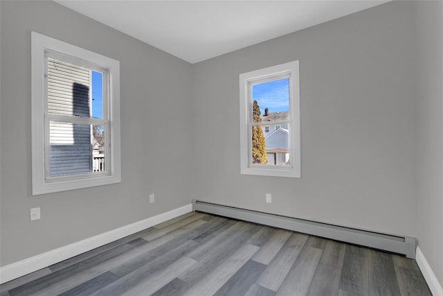 spare room featuring baseboard heating, wood finished floors, and baseboards