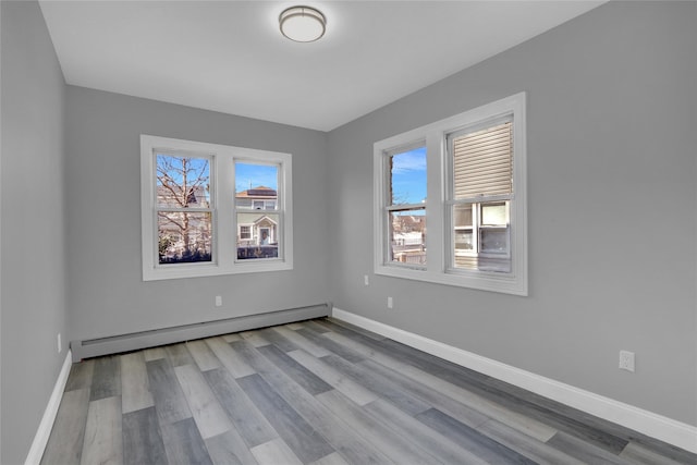 spare room featuring a healthy amount of sunlight, baseboards, and a baseboard heating unit