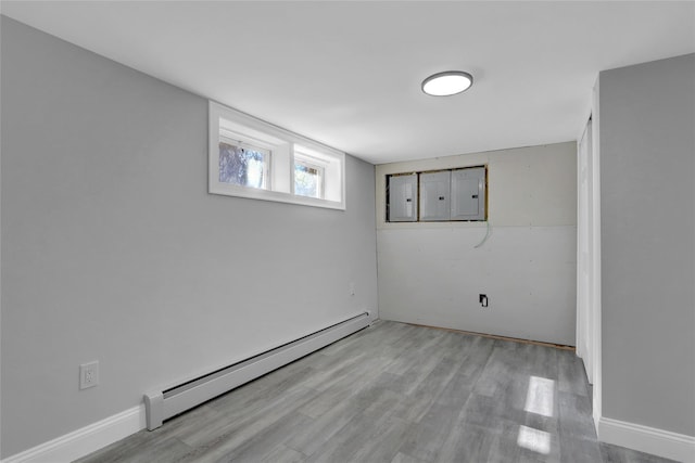 basement with baseboards, electric panel, a baseboard heating unit, and wood finished floors